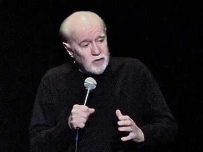 George Carlin performing one of his last shows in 2008 (CC BY-SA 2.0) Source: https://commons.wikimedia.org/wiki/File:Jesus_is_coming.._Look_Busy_(George_Carlin).jpg